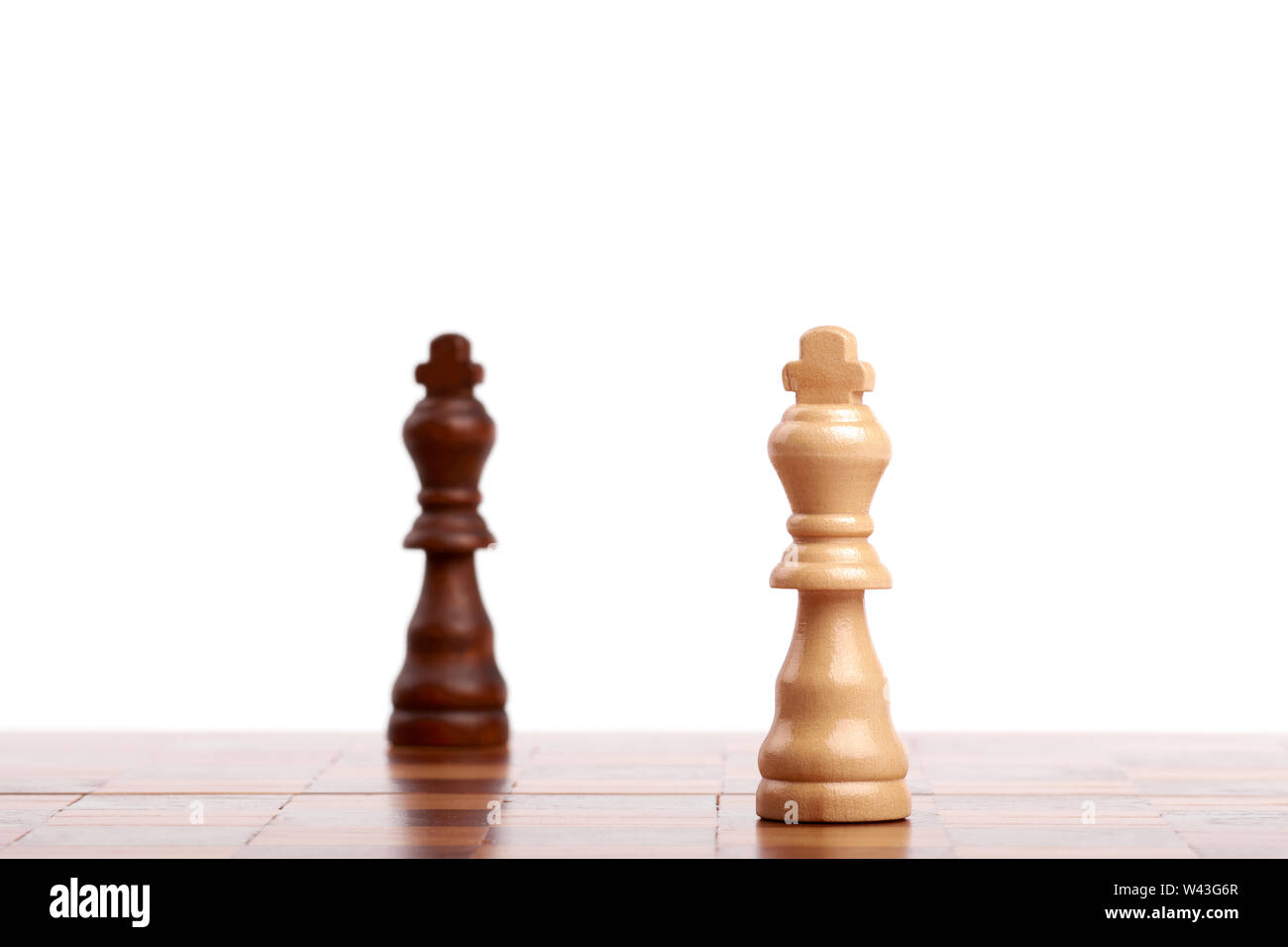 Zwei Holz- Schachfiguren, schwarze und weiße König auf dem Brett. Strategie und Sieg auf weißem Hintergrund. Stockfoto