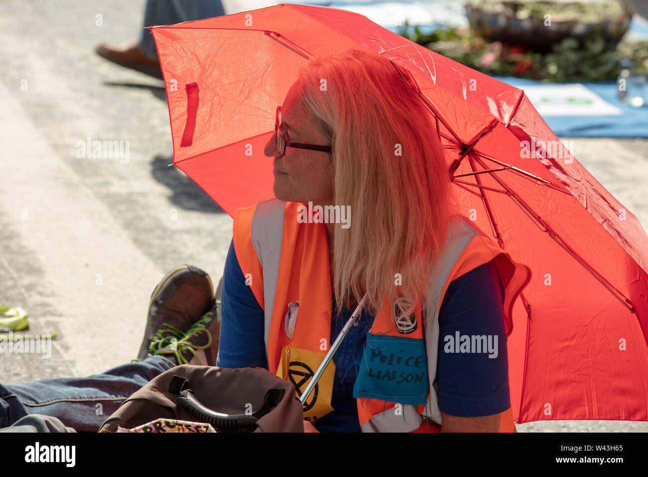 London, Großbritannien. 15. Juli 2019. Aussterben Rebellion Aktivist mit Regenschirm für Sonnenschutz, am Protest des Climate Action Group vor dem königlichen Gerichten auf dem Strand, London. Credit: Joe Kuis/Alamy Nachrichten Stockfoto