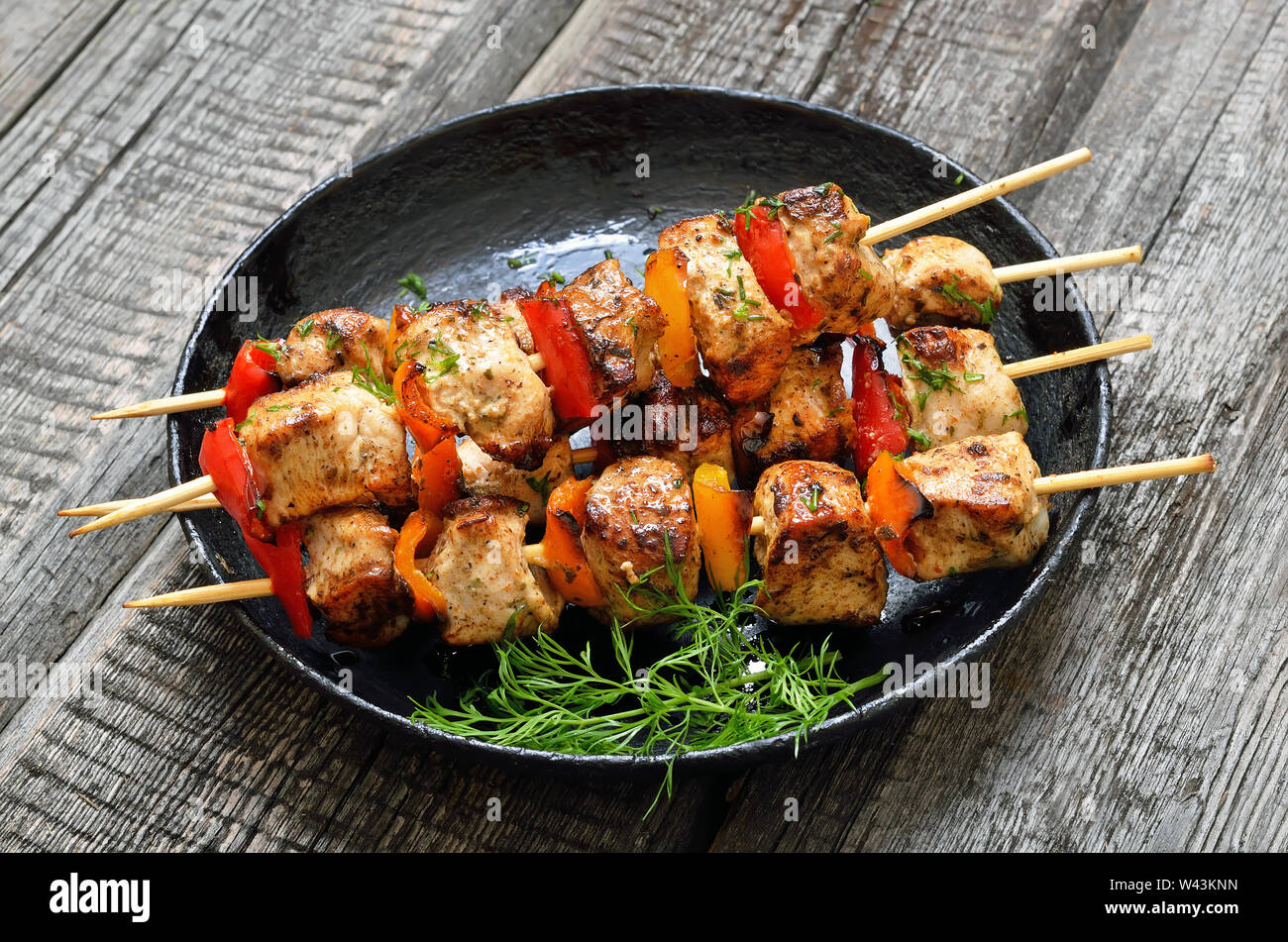 Chicken Kebab mit Paprika in einer Pfanne auf Holztisch, Nahaufnahme Stockfoto