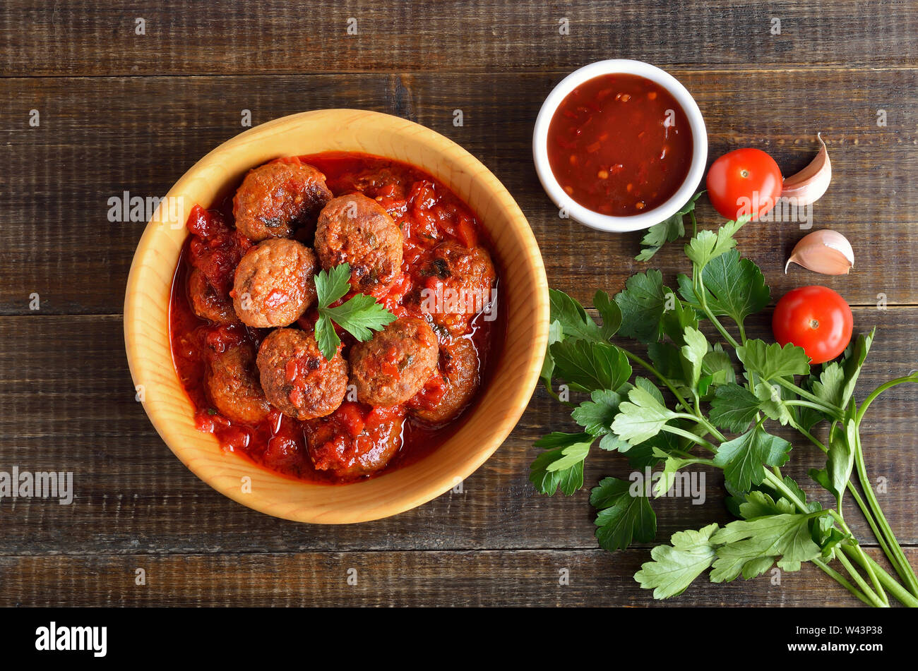 Lecker Frikadellen in Tomatensoße in Holz- platte, Tomatensauce und frischer Petersilie. Ansicht von oben, flach Stockfoto
