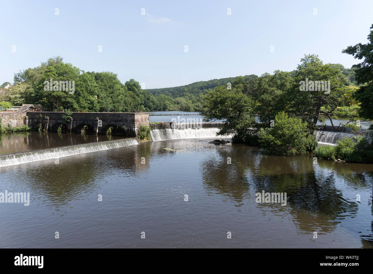 Die wehr und Schleuse in den Fluss Derwent neben alten Mühlengebäude in Belper, Derbyshire, England, Großbritannien Stockfoto