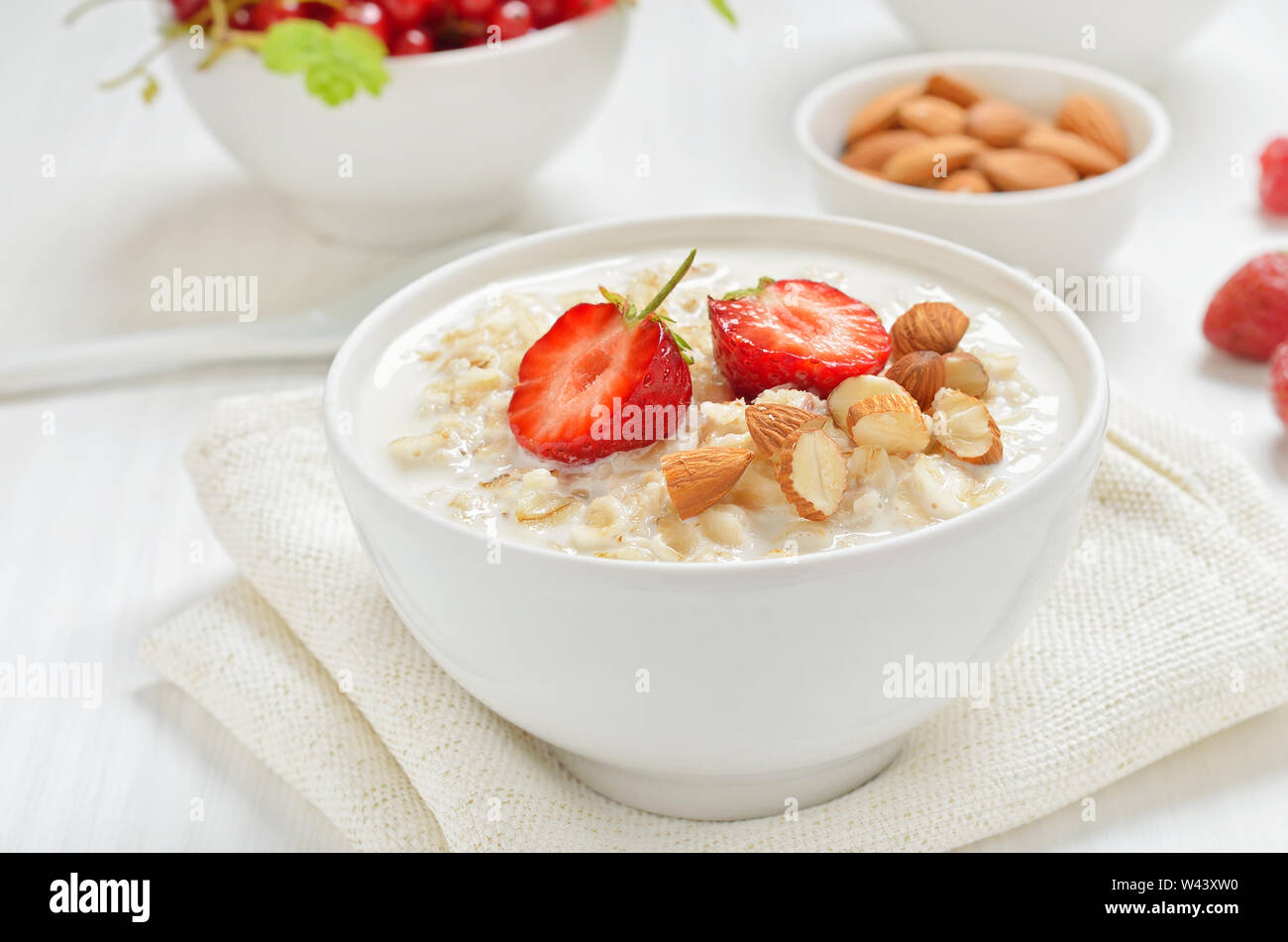 Haferflocken Porridge mit Erdbeere, Scheiben und Muttern in die Schüssel auf weißen Tisch Stockfoto