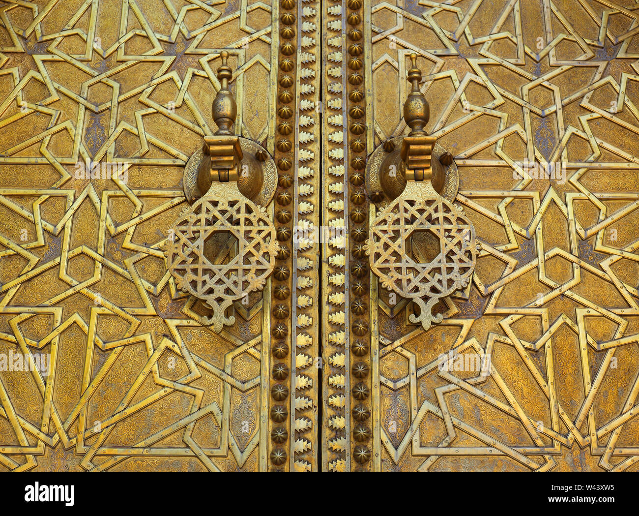 Marokko, Fes. Original alte Arabeske Stil Messing verkleidete Tür Detail mit islamischen symmetrische Muster und Tür klopft. Stockfoto