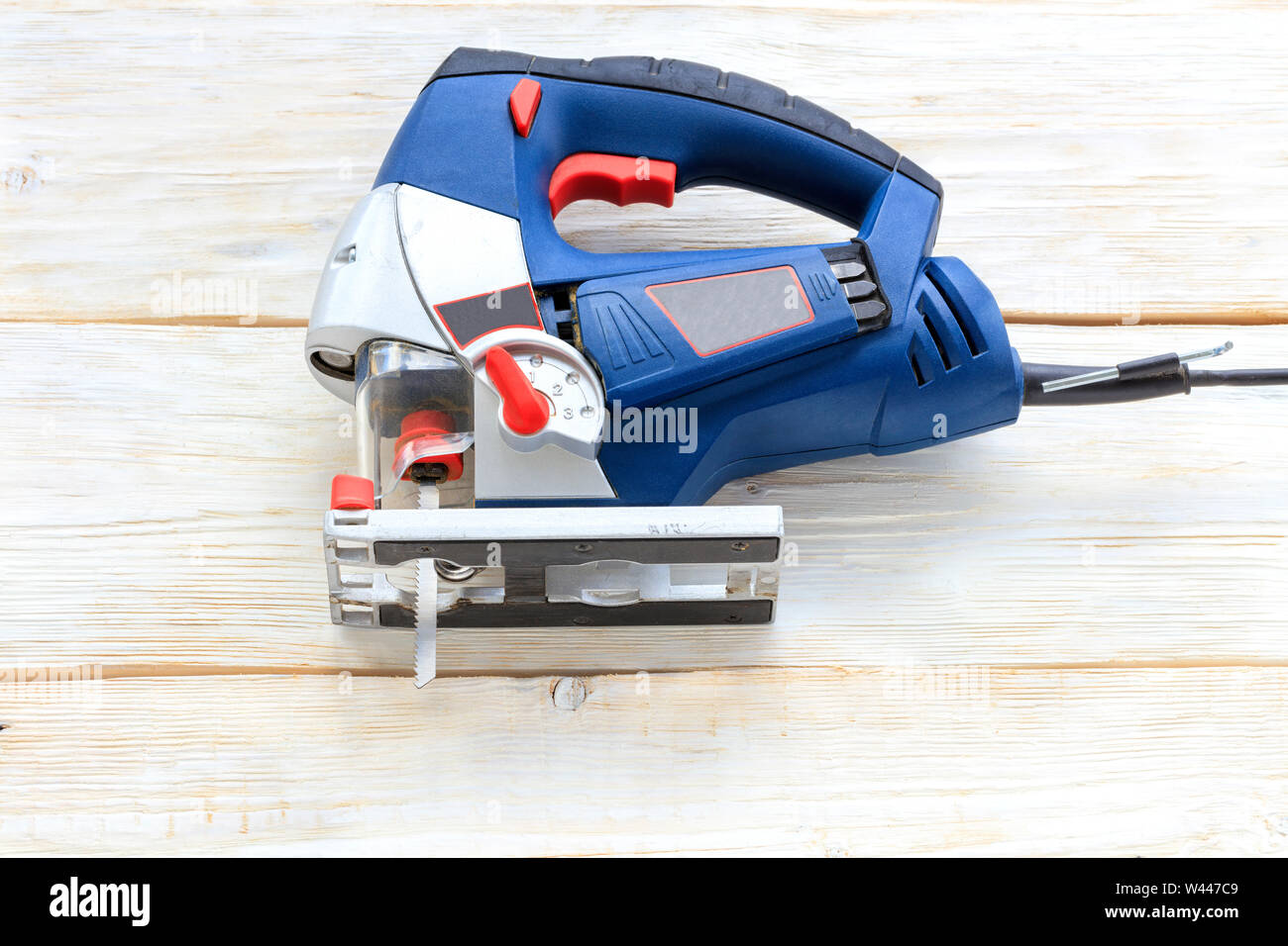 Eine alte professionelle elektrische Säge blaue Farbe liegt auf einem weißen Holztisch. Stockfoto