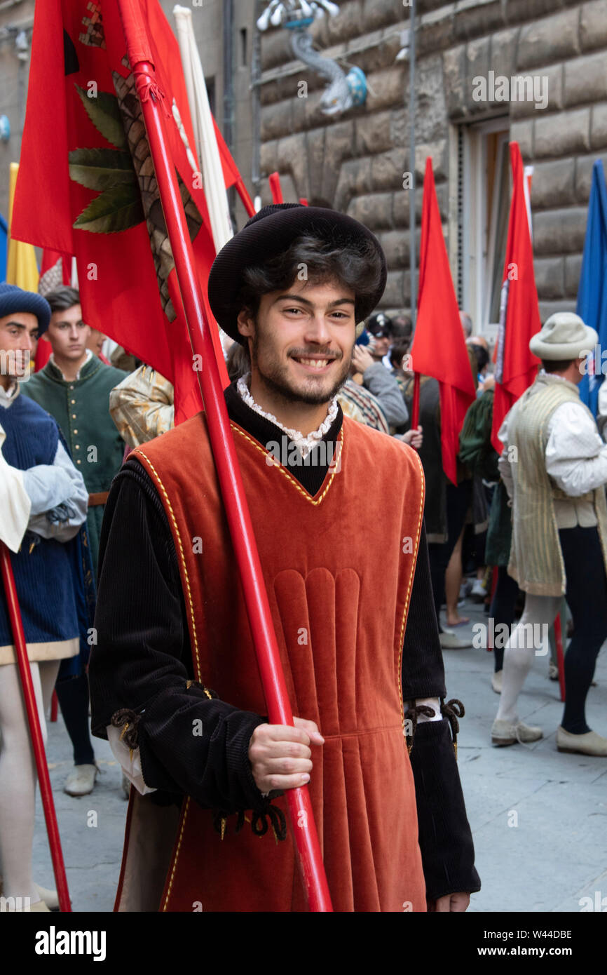 Mittelalterliche kostümierten gutaussehenden jungen Mann marschiert mit einer Flagge durch die Straßen von Siena, Italien bei der jährlichen historischen Palio Pferderennen und Parade Stockfoto