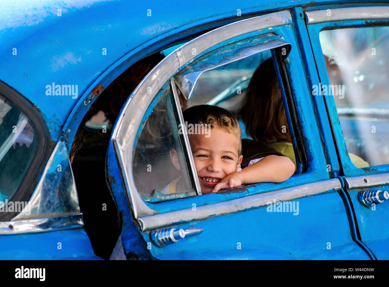 Kleinen kubanischen Jungen in den Rücksitz eines klassischen Kubanischen Auto sitzen lächeln Stockfoto