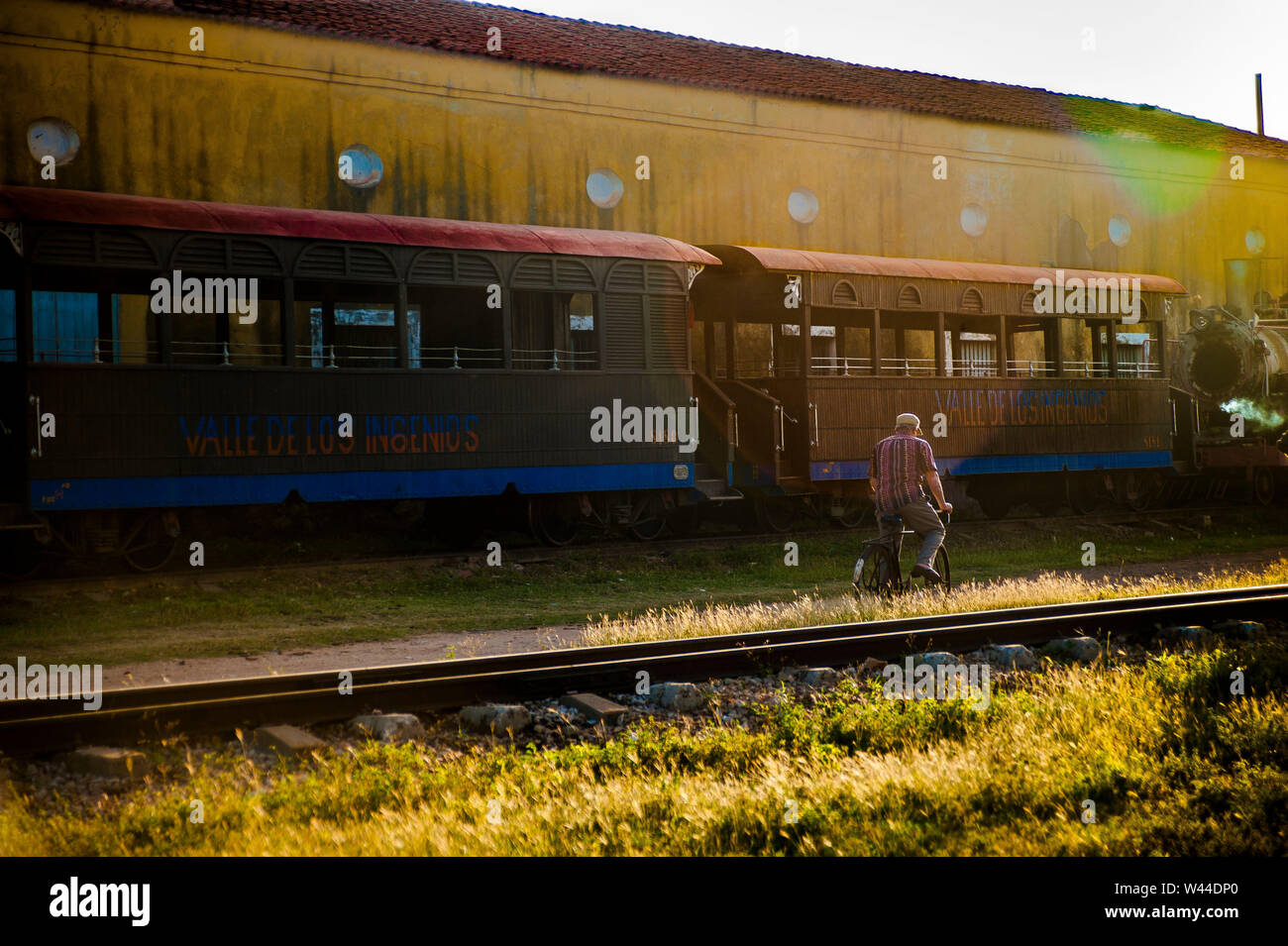 Mann reiten Fahrrad hinter einem Zug im Valle de los Ingenios in Trinidad, Kuba Sancti Spritus Stockfoto