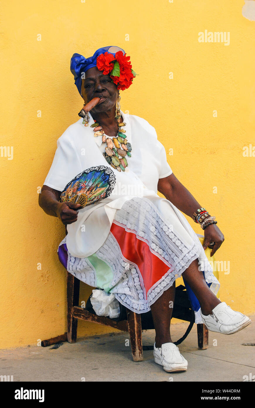 Kostümierte kubanische Frau in traditioneller Kleidung Posen und Rauch eine große Zigarre Stockfoto