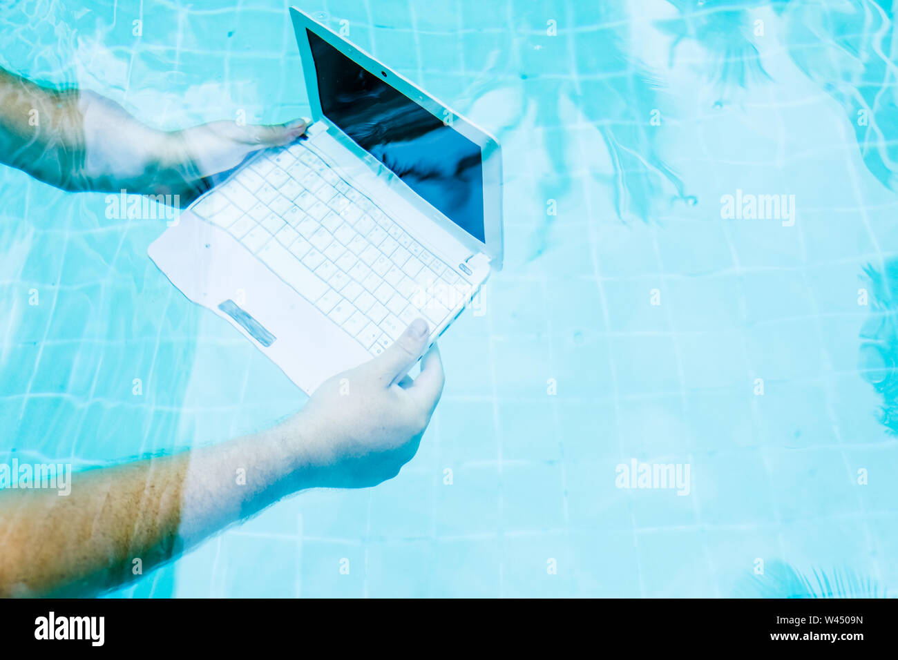 Männliche Hände mit einem Laptop arbeiten unter Wasser. Der Begriff der Behinderung in die Arbeit. Blur Abstrakt Hintergrund. Stockfoto
