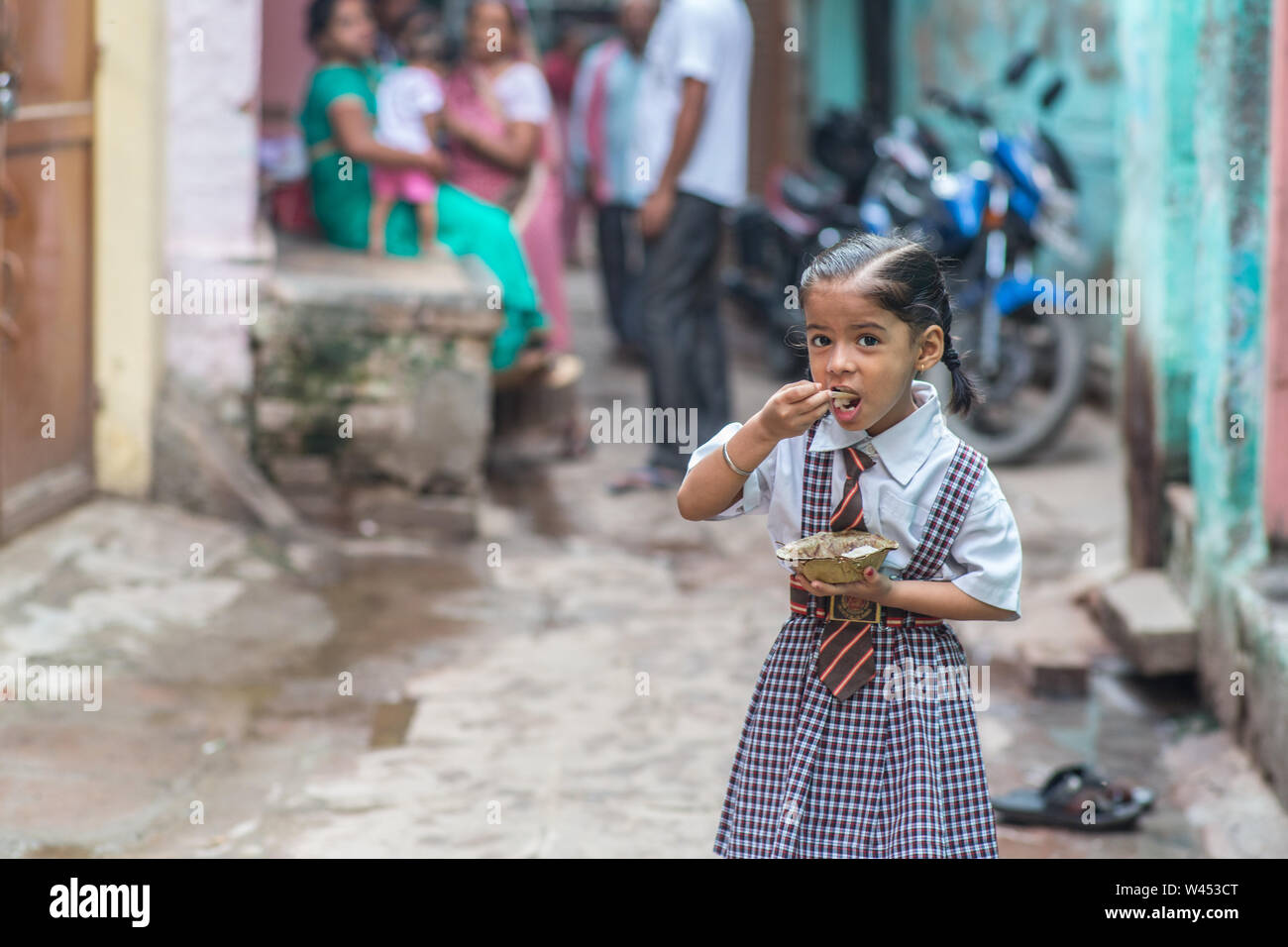 Ein kleines Mädchen essen idli zum Frühstück vor der Schule in Varanasi, Indien. Stockfoto