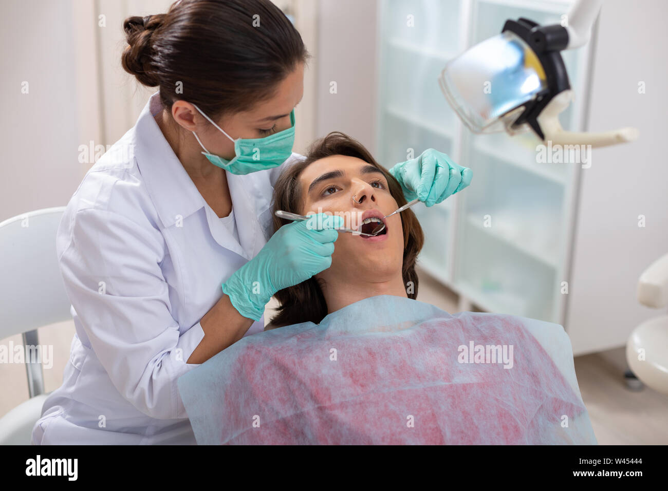 Konzentrierte sich Frau Zahnarzt beugte sich über Ihre männlichen Patienten Stockfoto