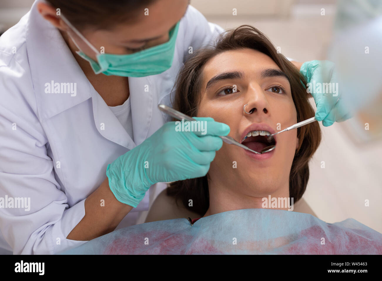 Dunkelhaarige gutaussehende jugendlich in einem Zahnarztstuhl liegen Stockfoto