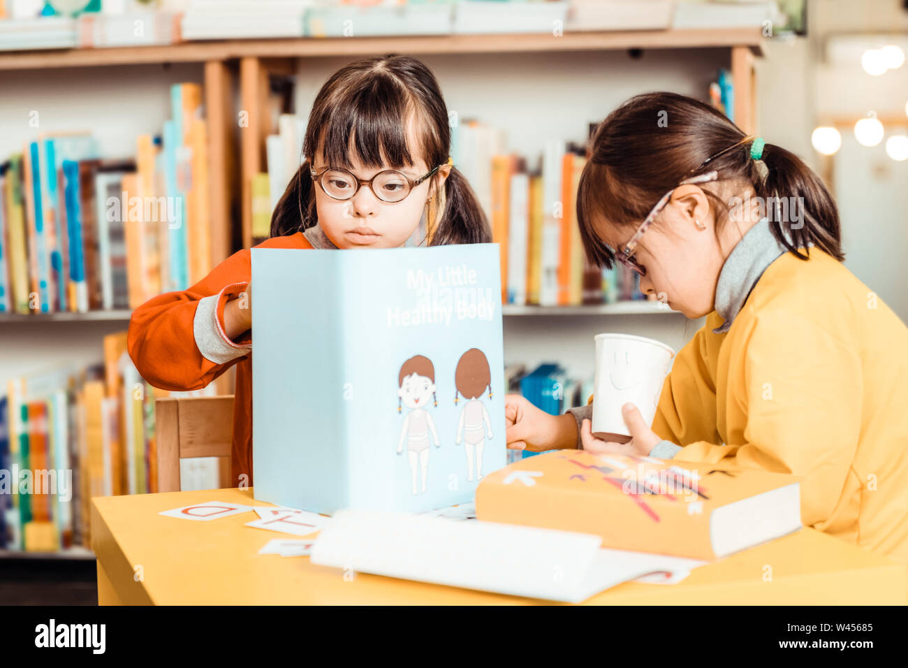 Dunkelhaarige Mädchen in hellen Hemden besetzt mit Lernmaterialien Stockfoto