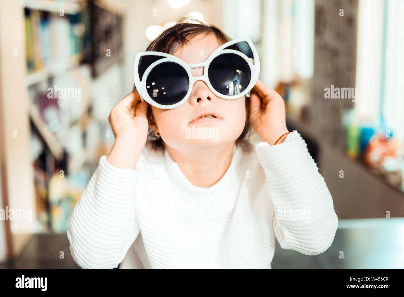 Kleines Kind mit Down-Syndrom tragen Big Cat-förmige Sonnenbrille Stockfoto