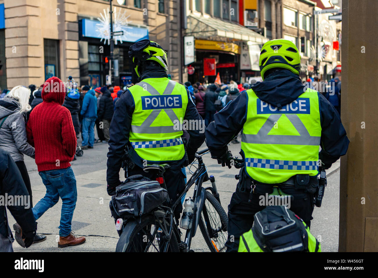 Eine Rückansicht der Polizeibeamten, die auf Fahrrädern gerade eine große Gruppe von Menschen in der Innenstadt, Umweltschützer demonstrieren Unscharf im Hintergrund zu sehen Stockfoto