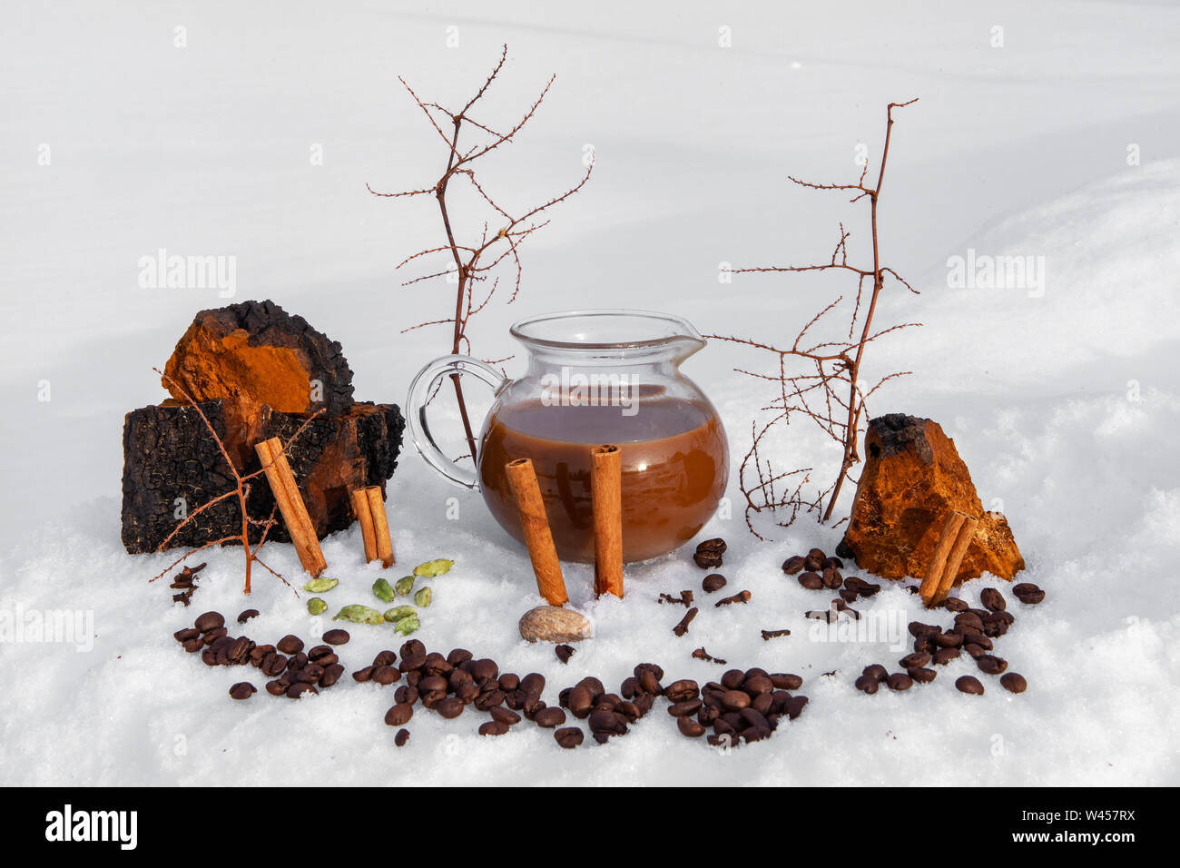 Kaffee- und Kakaobohnen gesehen liegen draußen im Schnee, mit Zimtstangen und natürliche Einrichtung durch eine Kanne gefüllt mit chaga chai latte, einem mystischen gebraut Trinken Stockfoto