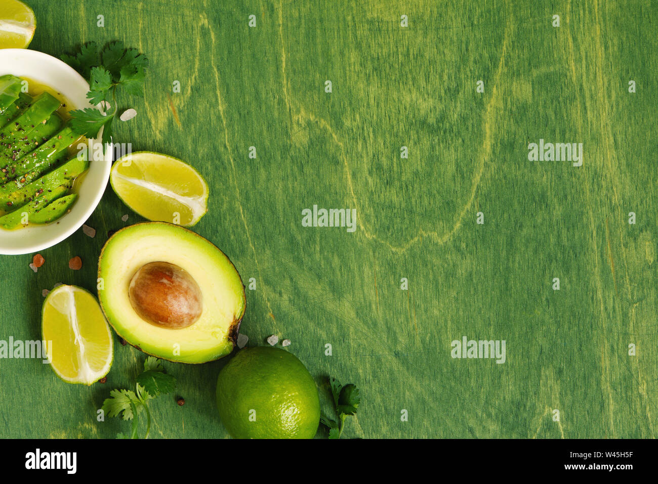 Grün Holz- Hintergrund mit frischen reifen Avocado, Kalk und Würzen, Ansicht von oben Zusammensetzung Stockfoto