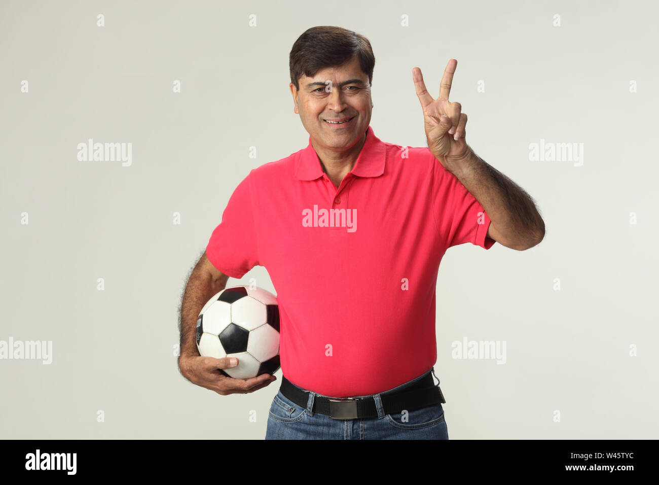 Porträt eines Mannes, der einen Fußball hält und zeigt Friedenszeichen Stockfoto