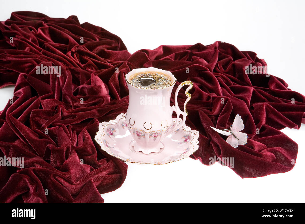 Tasse Tee, dunkel-rot Samt und Schmetterling auf einem Studio Hintergrund Stockfoto