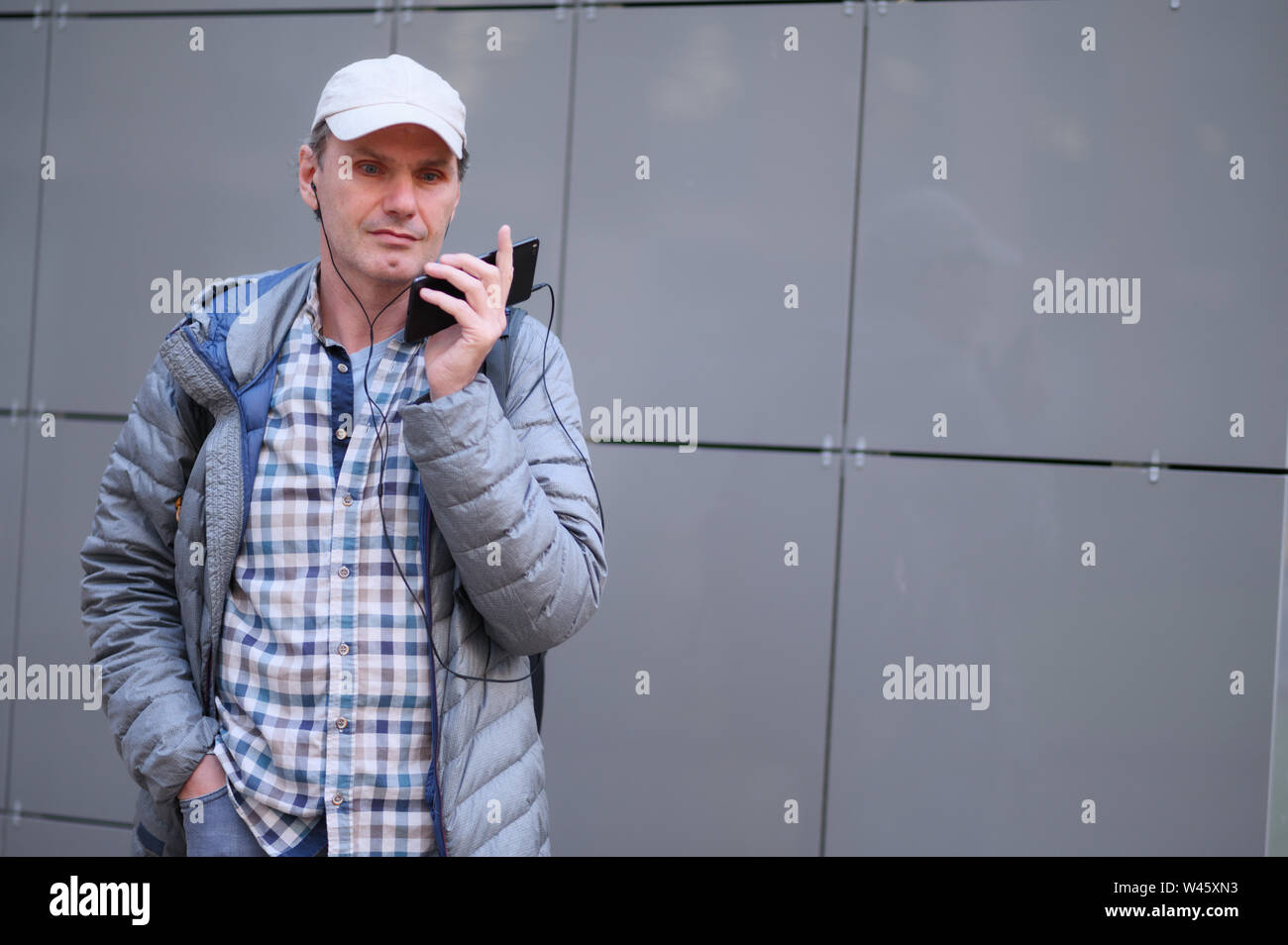 Reifer Mann mit Kopfhörern über Handy, authentische Auswahl unbearbeiteter Bild Stockfoto