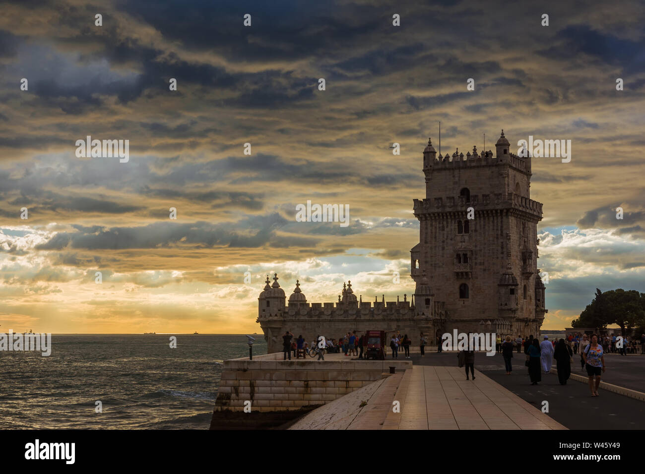 Touristen besuchen Sie die berühmten Belem Turm in der Nähe von Lissabon mit schönen Sonnenuntergang über dem Atlantischen Ozean Stockfoto