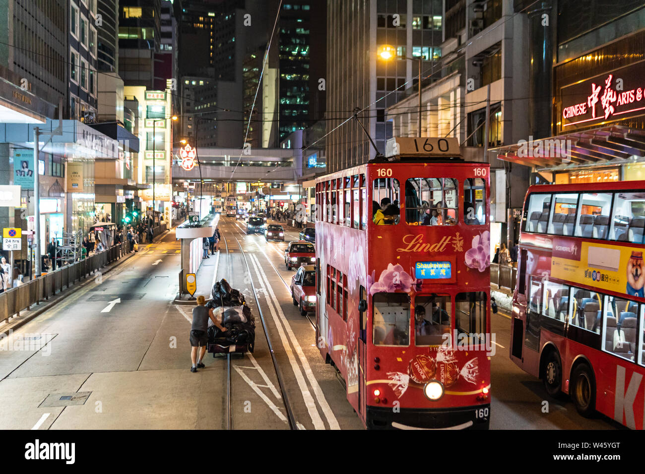 Hongkong, China - Macrh 15 2019: Straßenbahnen, Busse und Autos fahren im Herzen von Hong Kong Island Central Business District in der Nacht. Stockfoto