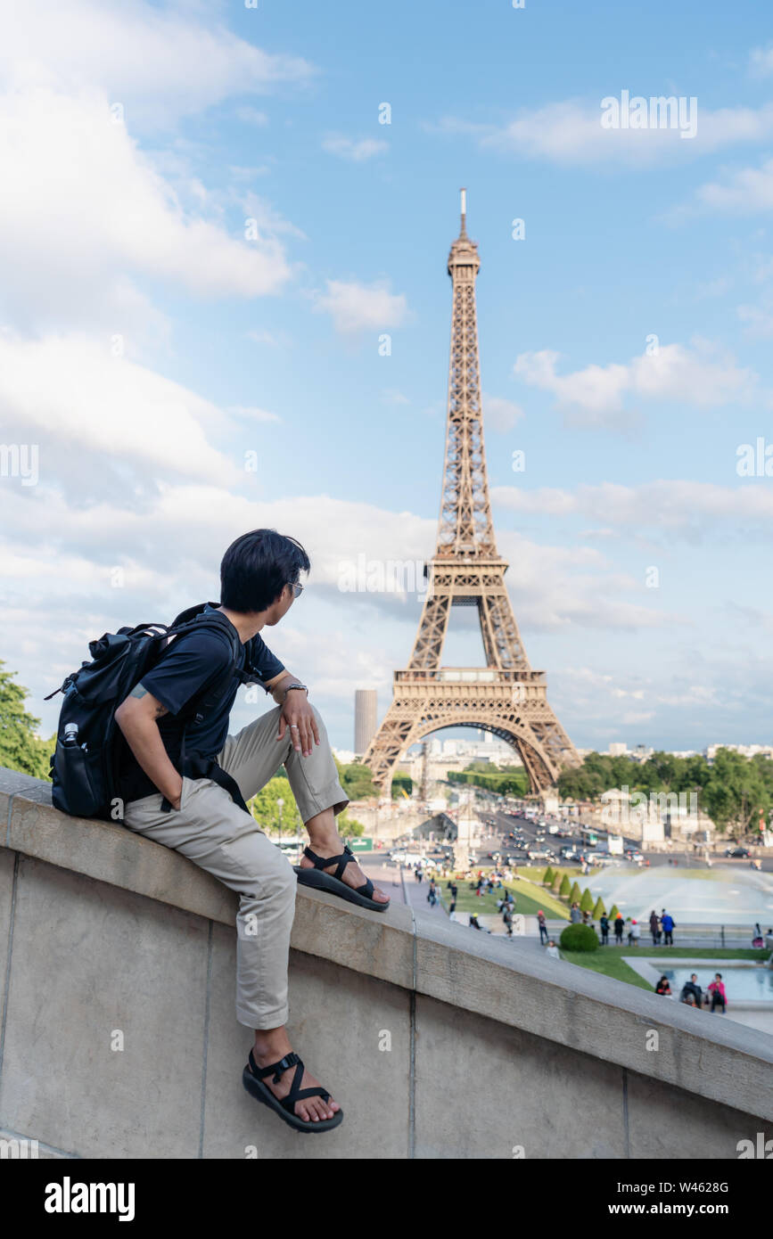Unterwegs in Europa im Sommer, ein Mann mit Rucksack am Eiffelturm suchen, Wahrzeichen und Reiseziel in Paris, Frankreich Stockfoto