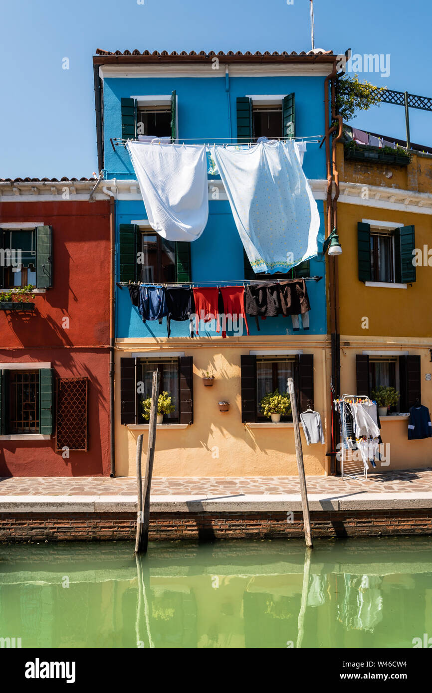 Wäsche trocknet an den Fassaden der bunten Häuser mit Reflexion im Canal, Burano, Venedig, Italien Stockfoto