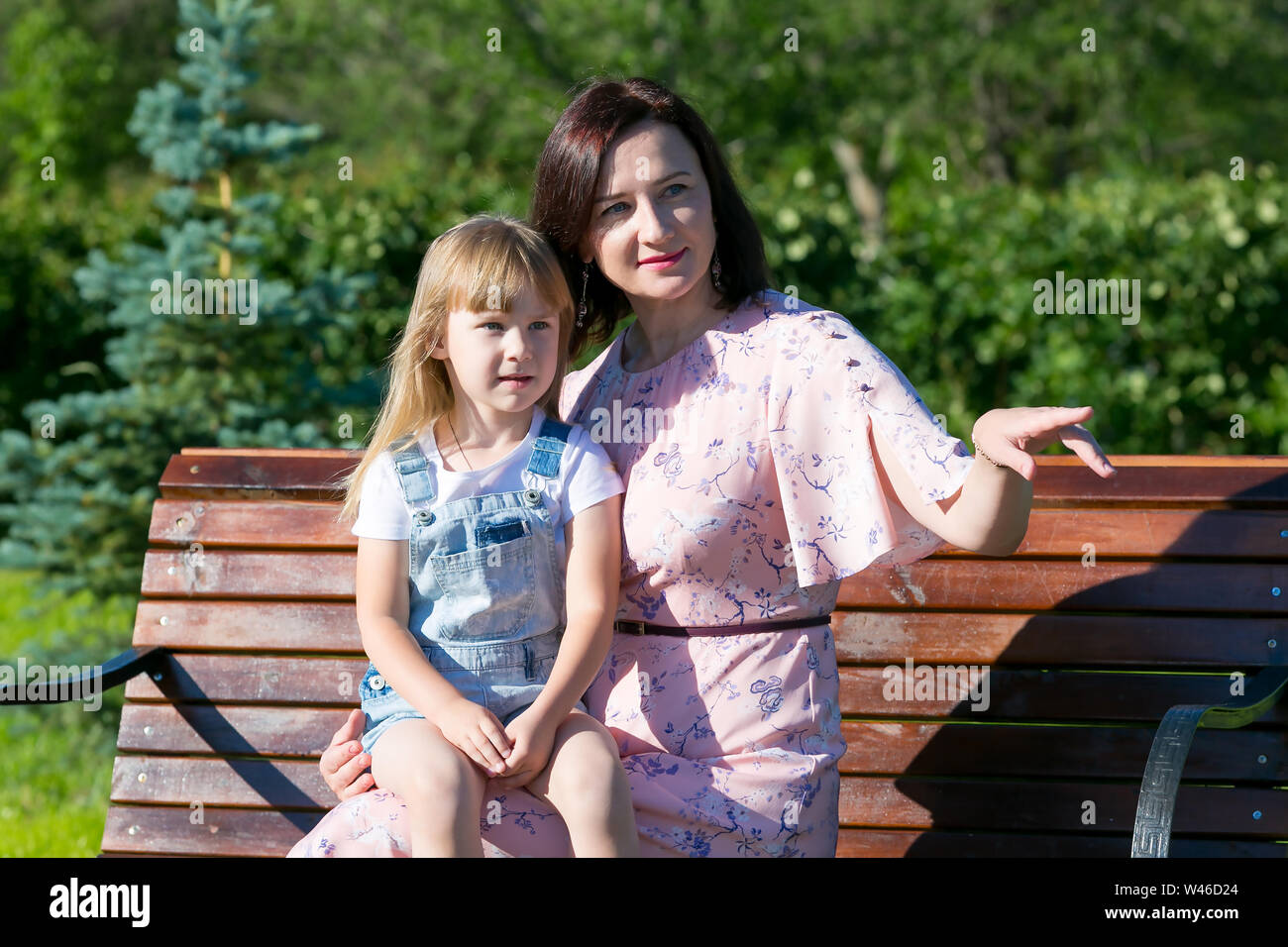 Junge Frau mit einem kleinen Mädchen auf einer Bank im Jahr Park. Stockfoto