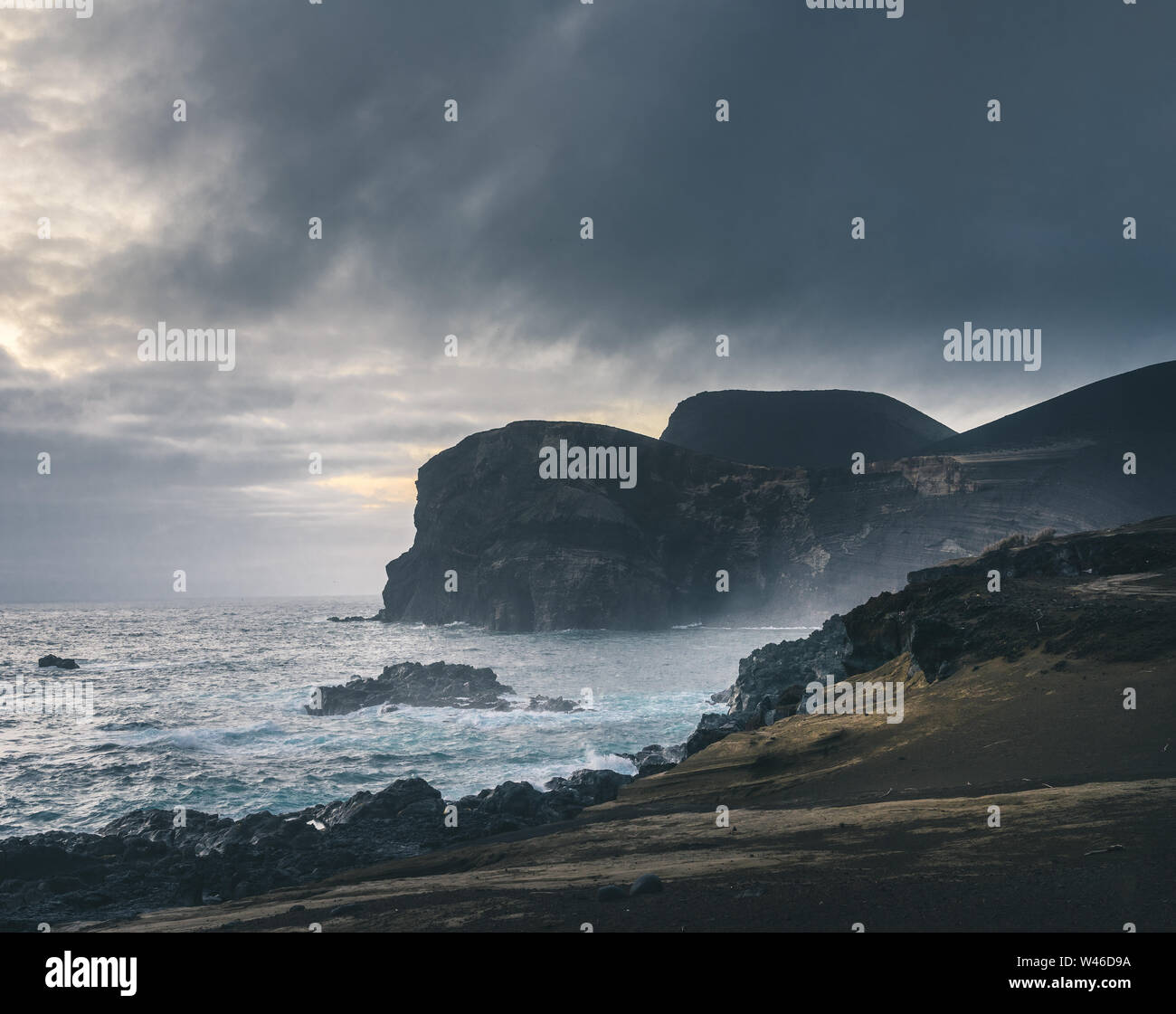 Blick über den Vulkan Capelinhos, Leuchtturm von Ponta Dos Capelinhos auf der westlichen Küste auf die Insel Faial, Azoren, Portugal mit einem dramatischen Sonnenuntergang und stark Stockfoto