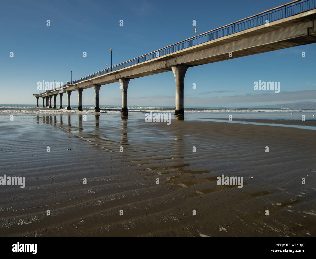 Modern New Brighton Pier, Neuseeland Südinsel, Im rippled nassen Sand mit blauen Himmel hinter wider Stockfoto