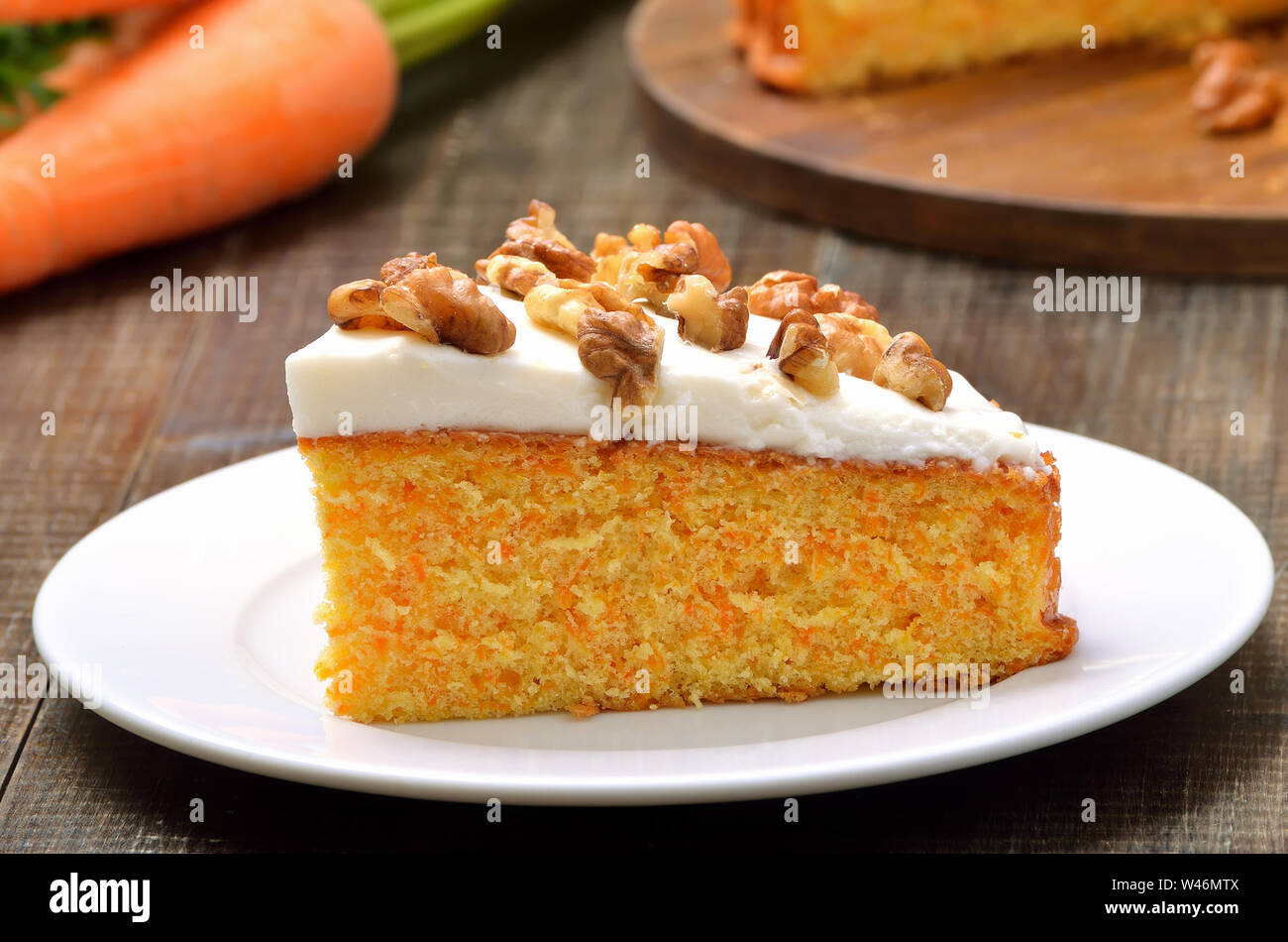 Stück Karottenkuchen mit Zuckerglasur dekoriert Walnuss auf weiße Platte, Nahaufnahme Stockfoto