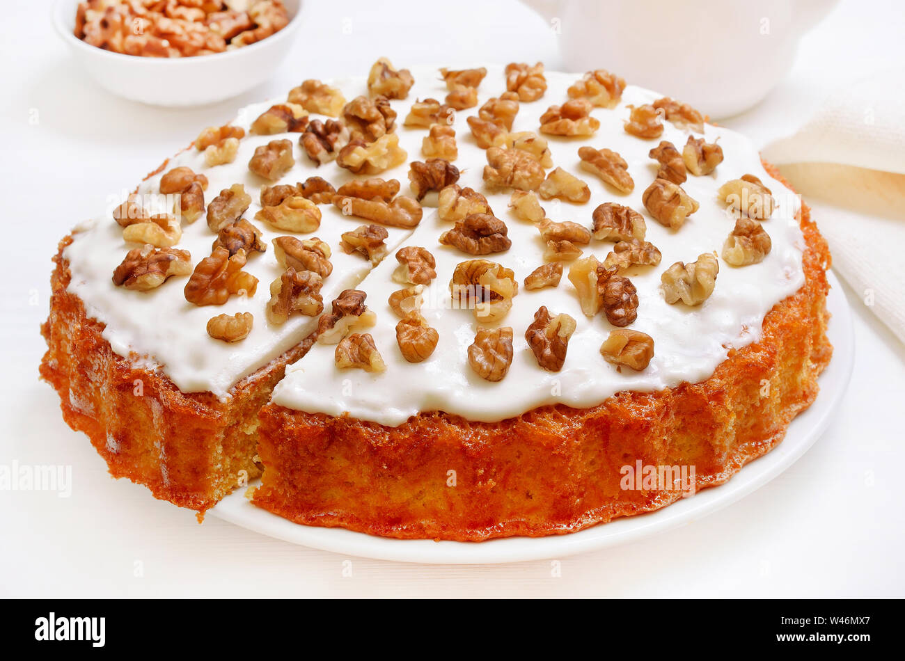 Appetitlich hausgemachter Karottenkuchen mit Zuckerglasur dekoriert Walnuss auf weiße Platte Stockfoto