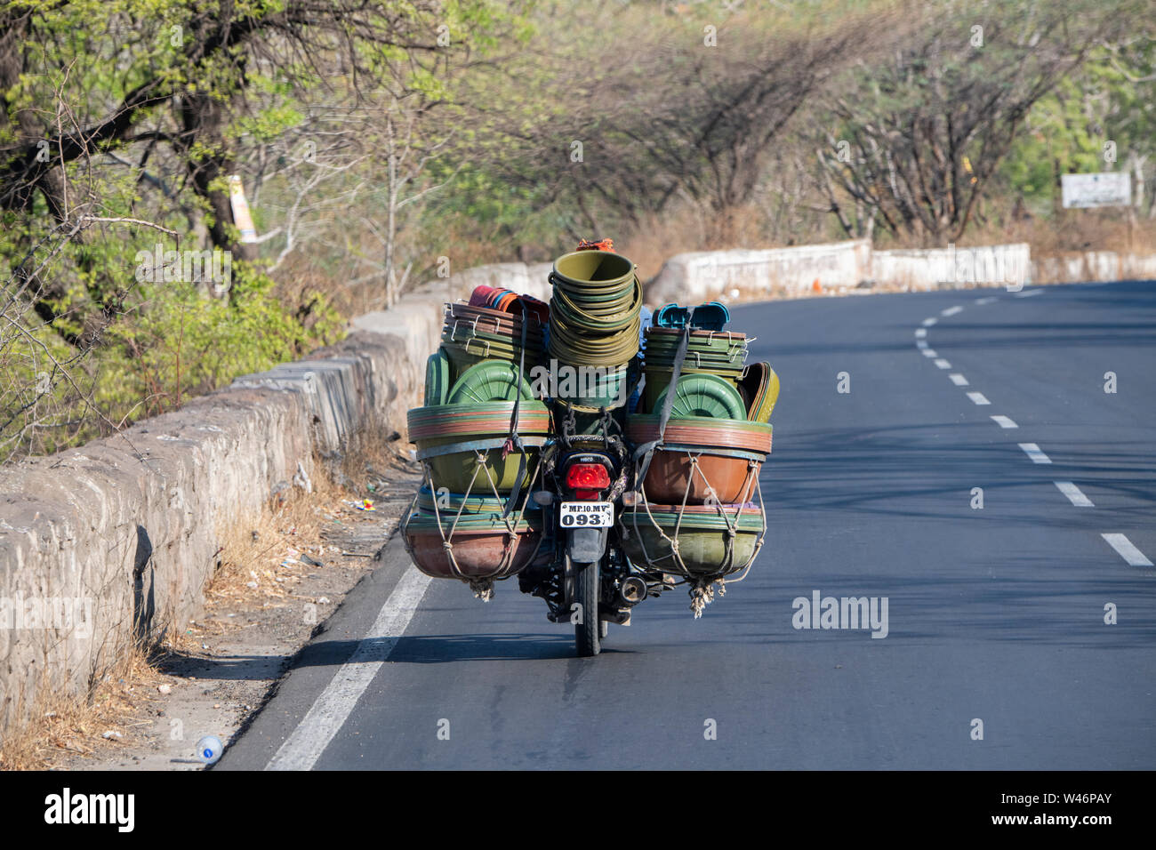 Indien, Bundesstaat Maharashtra, Aurangabad. Typische Straße Blick auf Motorrad mit einer vollen Ladung von Kunststoffbehältern. Stockfoto