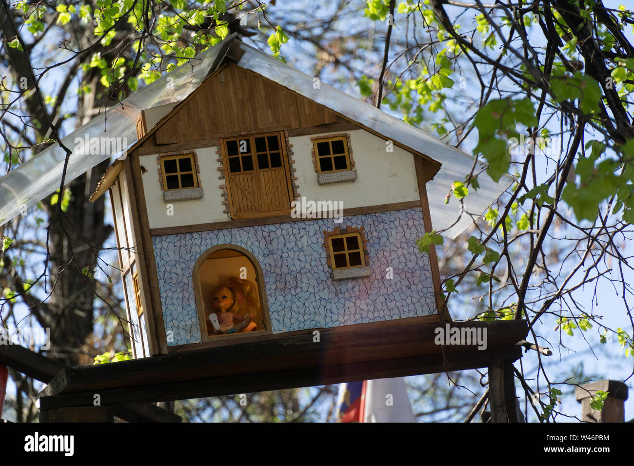 Holzspielzeug Haus hängen an einem Baum mit Baby Puppe in an einem sonnigen Tag Stockfoto