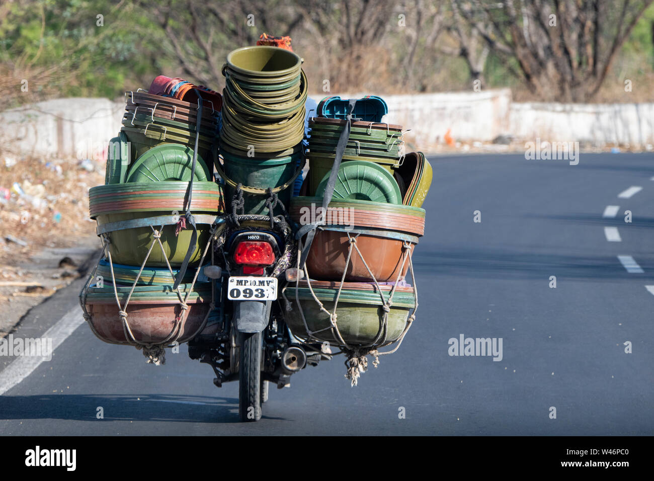 Indien, Bundesstaat Maharashtra, Aurangabad. Typische Straße Blick auf Motorrad mit einer vollen Ladung von Kunststoffbehältern. Stockfoto