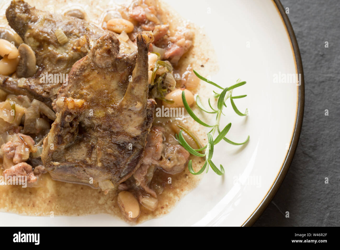 Ein Eintopf aus wilden Wald Tauben, Columba Palumbus, Kochen, Zwiebeln, Speck, Rindfleisch enthält Cannellini Bohnen, in Scheiben geschnittenen Champignons und frischen Ro Stockfoto