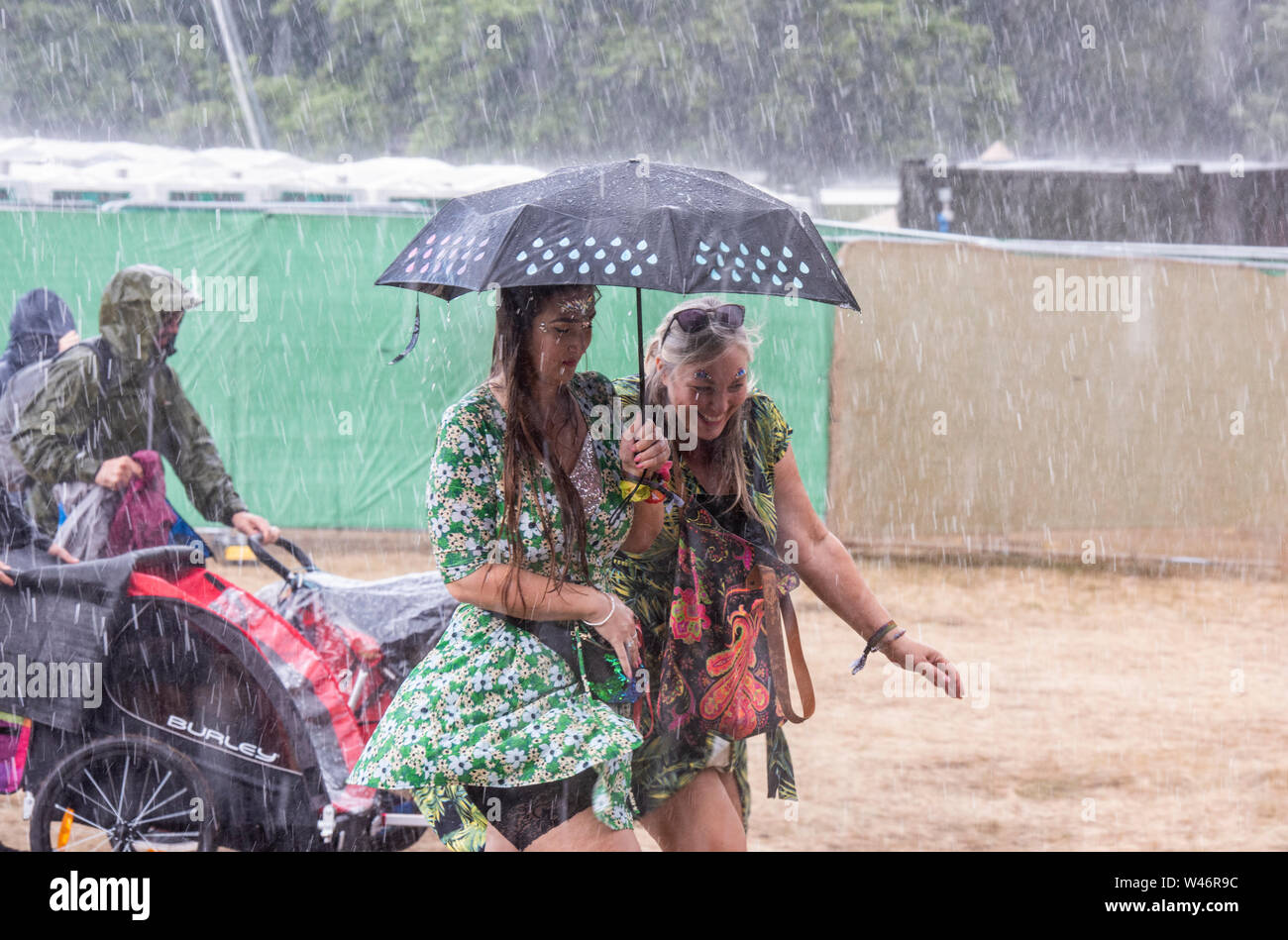 Festivalbesucher laufen für Schutz vor massiven unerwarteter Regenguß, Latitude Festival, henham Park, Suffolk, Großbritannien am 20. Juli 2019 Stockfoto