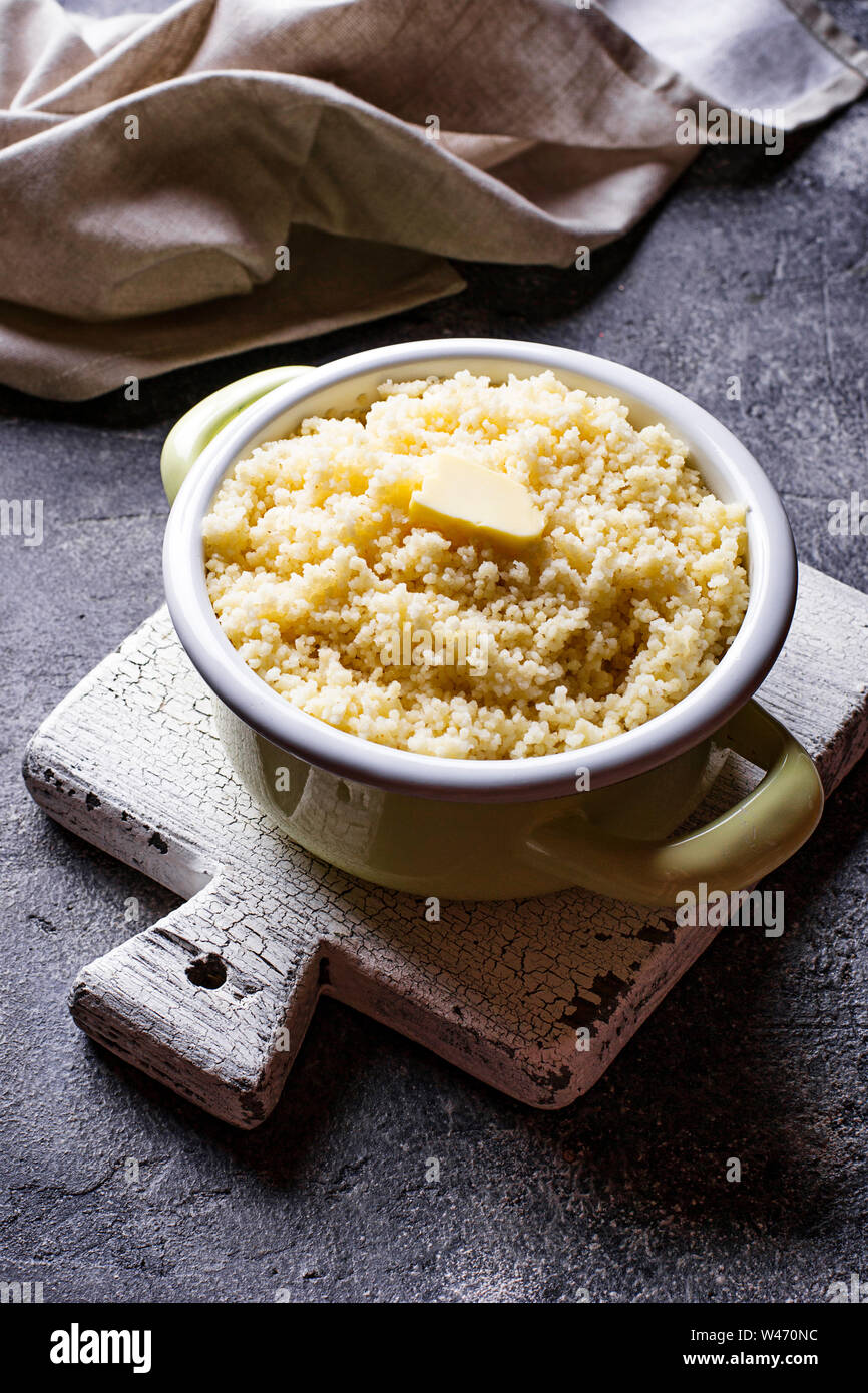 Couscous mit Butter im Topf auf dunklem Hintergrund Stockfoto