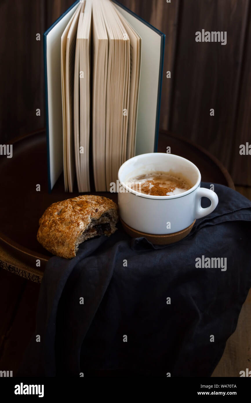 Leckeren snack Croissant mit Marmelade und Kaffee, mit einem Buch auf rustikalen und Holz eingerichtet. Stockfoto