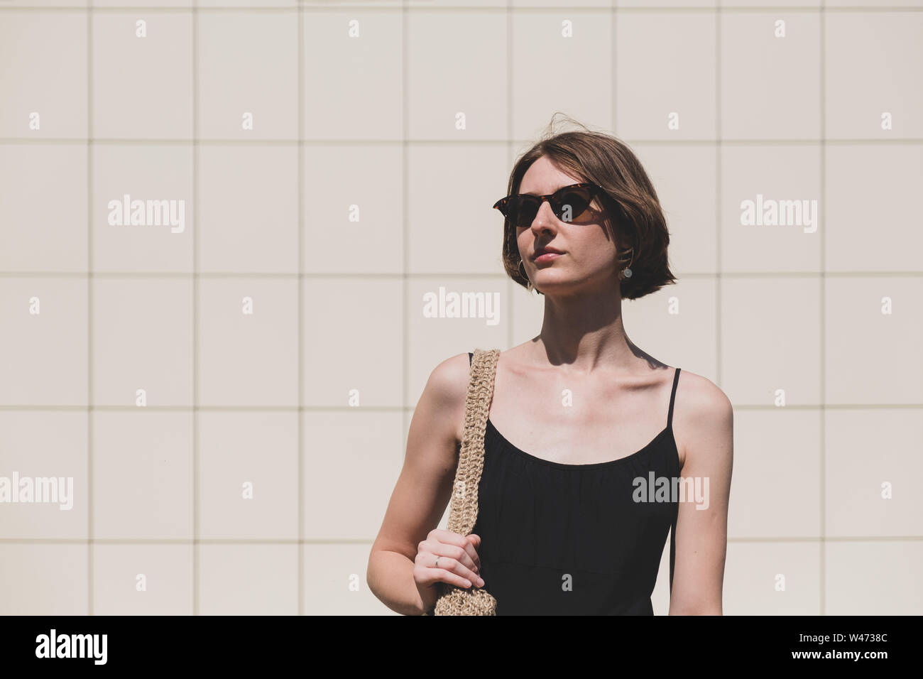 Junge selbstbewusste Frau portrait. Weibliche Person in einfachen schwarzen Kleid in minimalistisch im städtischen Hintergrund Stockfoto
