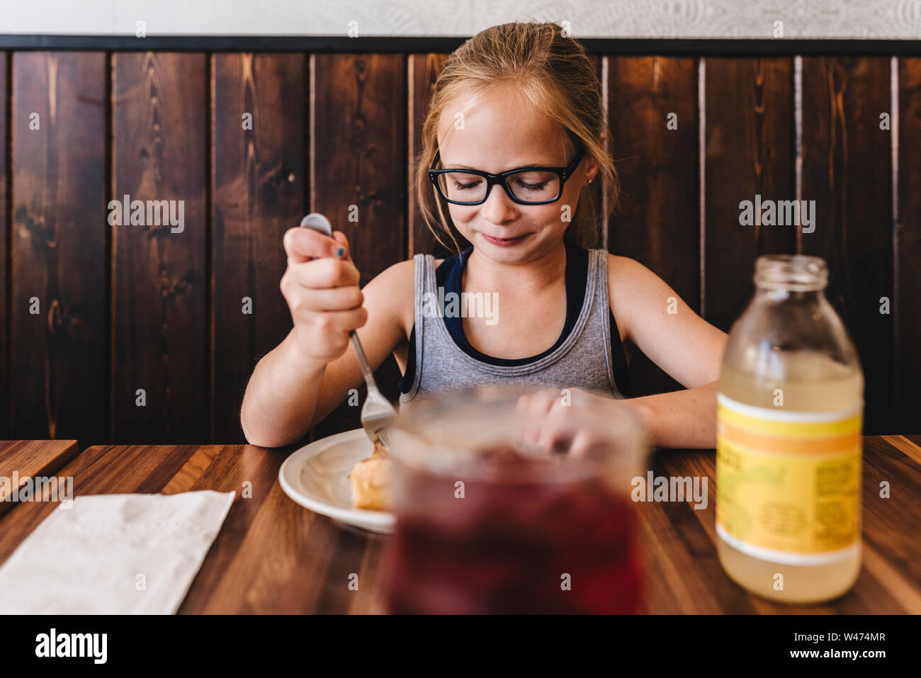 Kleines Mädchen isst und trinkt am Tisch im Cafe Restaurant. Stockfoto