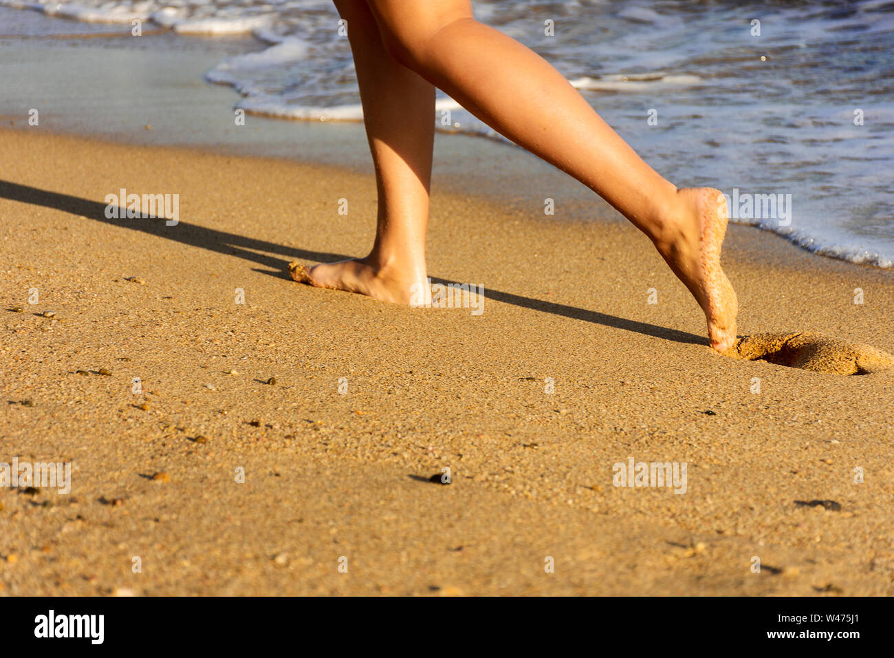 Junge Frau zu Fuß am Strand. Sand und Wasser. Stockfoto