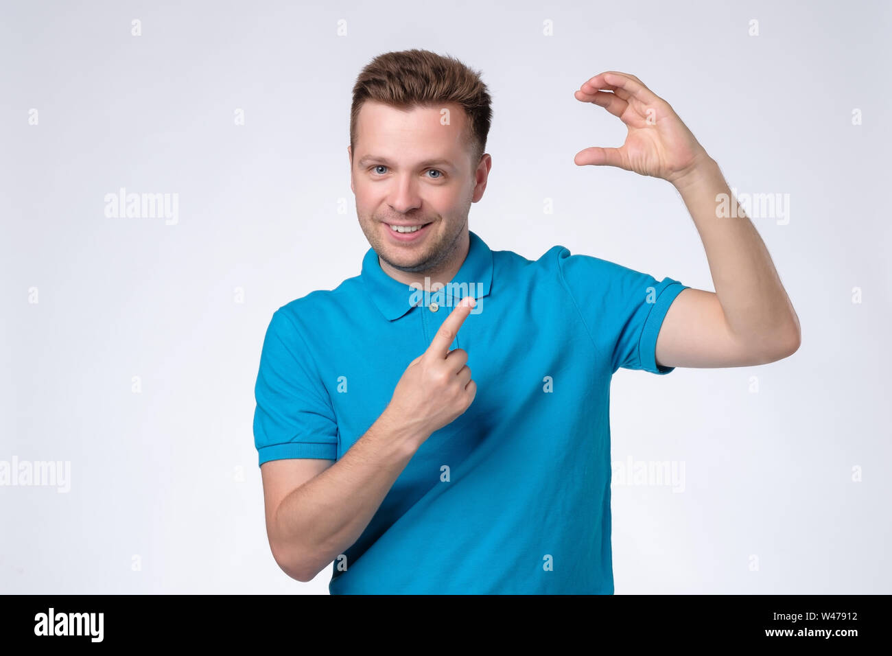Jungen kaukasischen Mann im blauen T-Shirt zeigt auf leeren Platz für Ihre Karte oder Ad. Stockfoto
