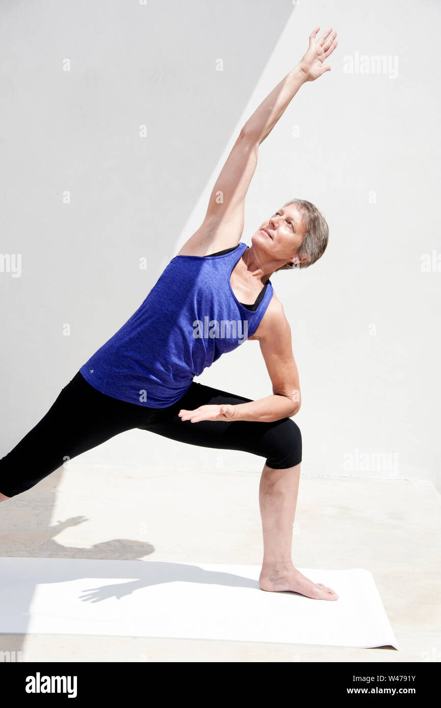 Reifer senior Frau practing Sanfte restorative Yoga in weißem Hintergrund fotografiert. Stockfoto