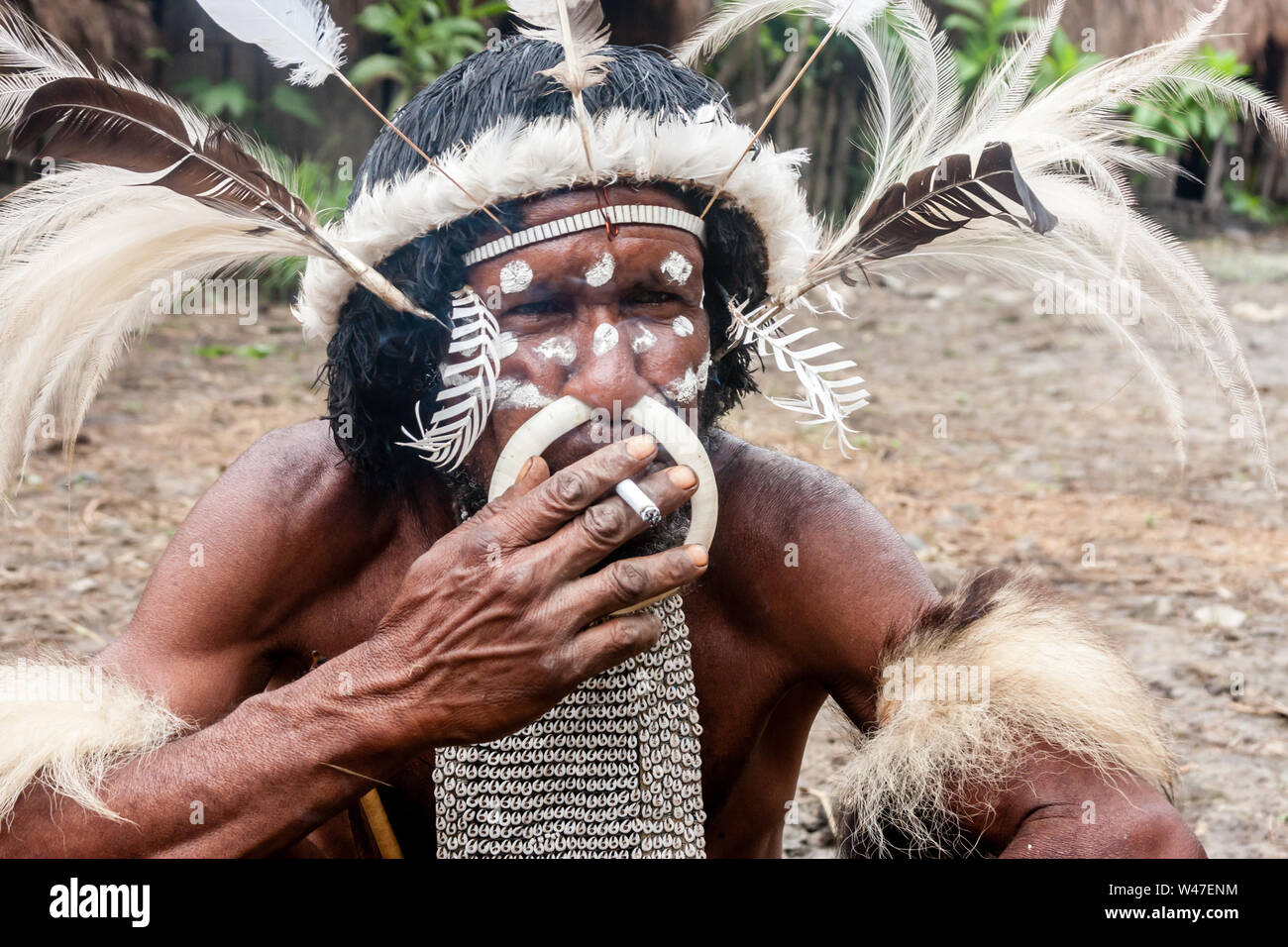 Wamena, Indonesien - Januar 9, 2010: Der Leiter der Dani Stamm in ein traditionelles Kleid das Rauchen einer Zigarette in Dugum Dani Dorf. Das Baliem Valley Papua Stockfoto