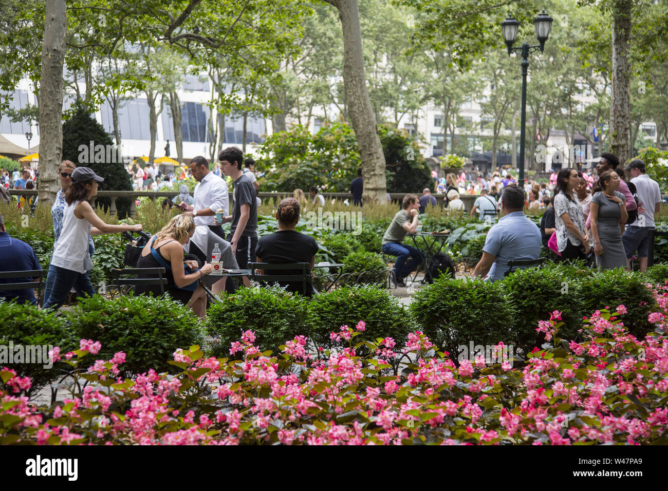 Midtown Büroangestellte und Touristen entspannen im Bryant Park am Mittag in Manhattan, New York City. Stockfoto