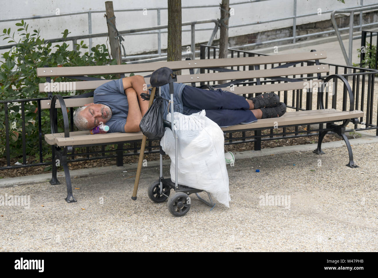 Man schläft auf einer Bank mit einem Kunststoff Flasche als Kissen auf Coney Island, Brooklyn, New York. Stockfoto