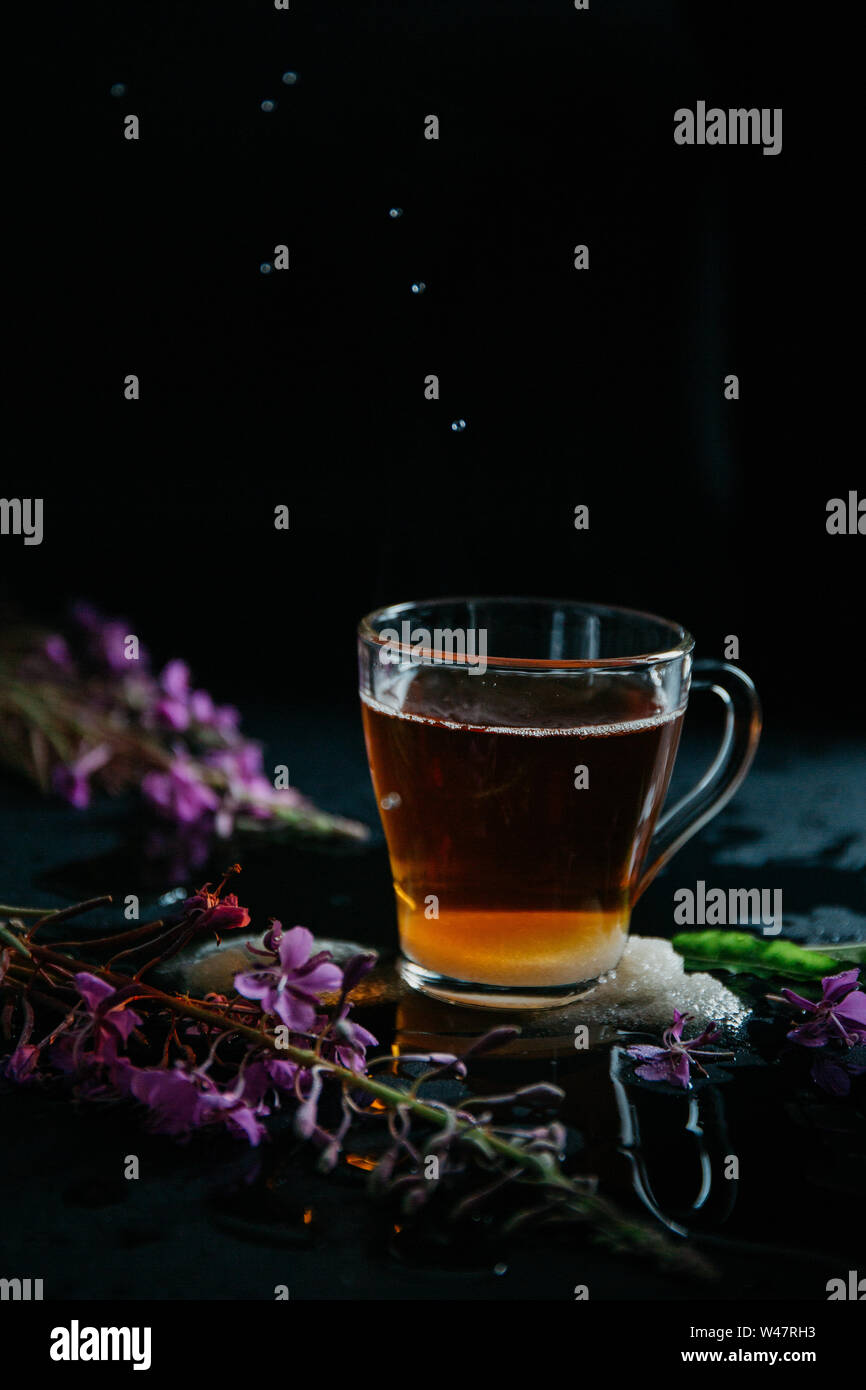 Glas Tasse braunen schwarzen heißen süßen Tee mit Blasen und Spritzer aus geworfen lösen Stück Zucker und zwei Stücke von weißem Zucker. Blühende Sally Stockfoto