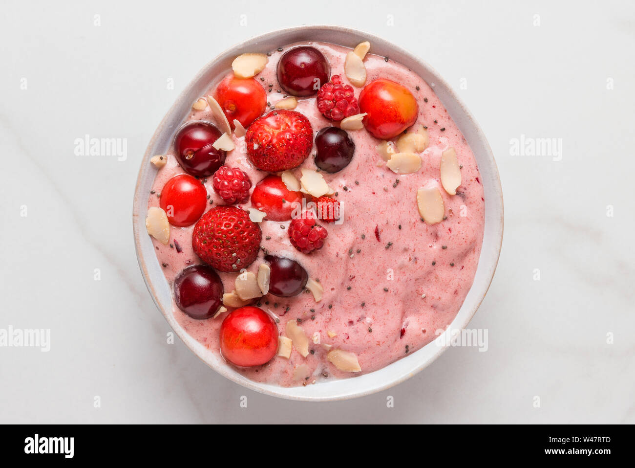Smoothie Schüssel oder Nizza cream gefrorene Bananen und Beeren mit frischen Beeren, Nüsse und Samen auf weißem Marmor tisch. gesundes Frühstück. top View Stockfoto